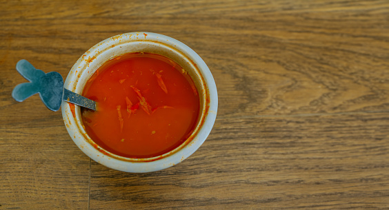 Flat lay of Bowl of hot sauce on wooden table. Copy space.