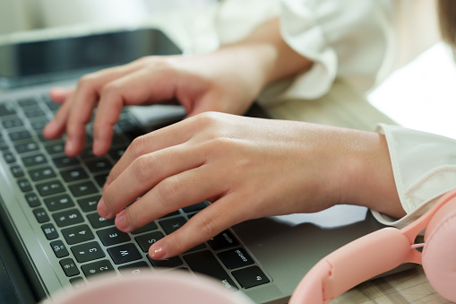 Close-up of young woman's hands typing on laptop, narrative of modern remote work and technology. Delicate hands of female work swiftly on laptop keys, symbolizing the digital era's connectivity