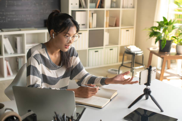 istock Young Asian teacher transforms her living space into an engaging online classroom,  teaching online with passion, concept of online teaching and education. 1982477381