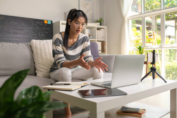 istock Young Asian teacher transforms her living space into an engaging online classroom,  teaching online with passion, concept of online teaching and education. 1982477408