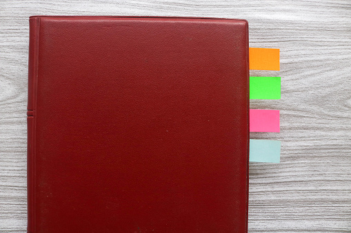 Colorful sticky notes between books. Colorful sticky note bookmarks are attached to the notebook. Bookmarks in a book on wooden table