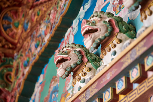 Snow lions with turquoise manes bas reliefs on wall above entrance to Buddhist temple, decorative and religious decoration of ancient temple facade, snow lions mythological celestial animal of Tibet