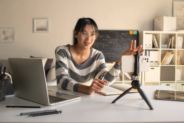 istock Young Asian teacher transforms her living space into an engaging online classroom,  teaching online with passion, concept of online teaching and education. 1982529420
