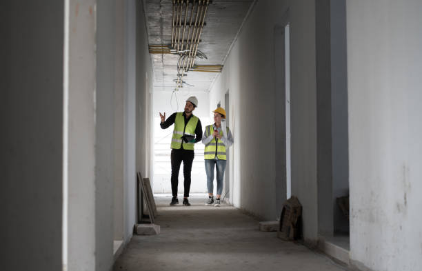 istock Caucasian engineer man and woman working with tablet computer and paper work in building at construction site 1982538491