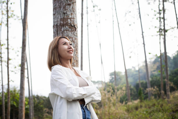 istock Asian woman standing under the tree and looking at far away 1982543898