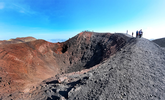 Italy: hikers walking on the edge of one of the craters of Mount Etna, the sicilian active vulcano, in the province of Catania.
