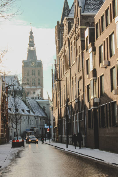 Den Bosch, the Netherlands / January 2024: the bus driving through the Sint Josephstraat in 's-Hertogenbosch on a very rare snowy day. The church tower is the city’s landmark, Sint-Janskathedraal ( St John’s basilica).