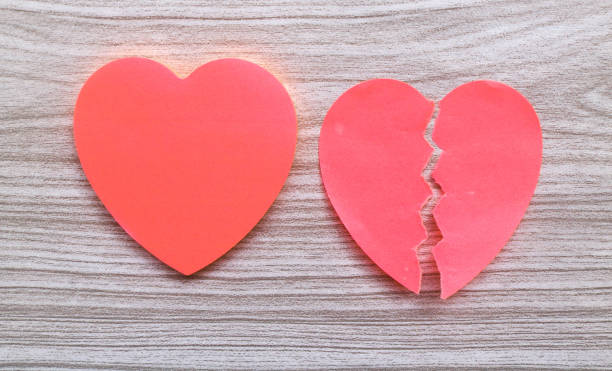 istock Two pink heart sticky note hanged on wooden background. Broken heart shape sticker. Blank space love stick note for writing 1982577385