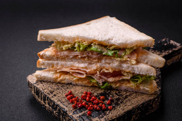 istock Delicious nutritious sandwich with toast bread, ham, tomatoes, cheese and sauce 1982580452