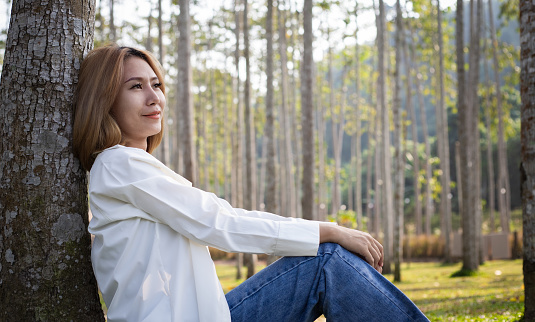 Happy moment hipster woman relaxing and sitting under the tree on forest ,enjoying time on holiday concept