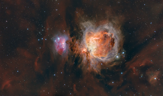 Astrophotography made with telescope of the Orion Nebula, Messier 42 or M42 together with the running man nebula. Many stars and glowing red hydrogen and blue oxygen gas in space. High quality photo