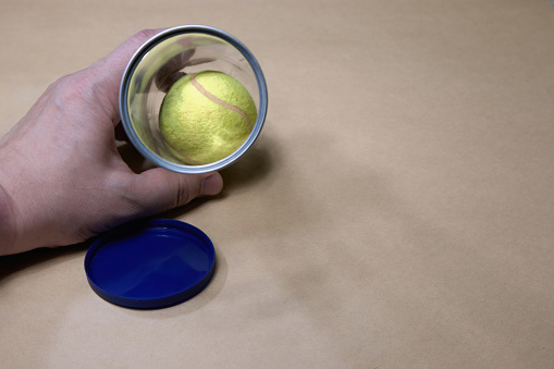 A hand holds a special tube with a tennis ball. Tennis match, start of a tennis tournament, tennis background, mockup