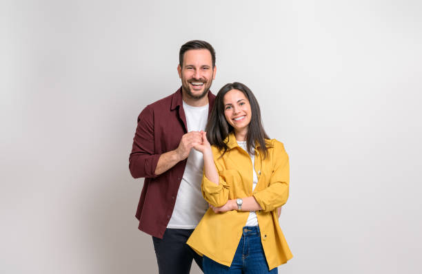 retrato de novio y novia jóvenes románticos tomados de la mano y sonriendo sobre fondo blanco - heterosexual couple love romance couple fotografías e imágenes de stock