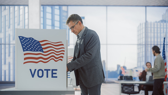 Respectable Adult Man Filling Out His Ballot. American People on the Elections Day in the United States of America. Diverse People Using Voting Booths to Cast Their Vote for a Preferred Candidate
