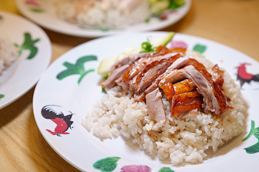 In a close-up view, a plate of Asian-style Roasted Duck over Rice is featured, showcasing the succulent and flavorful dish.