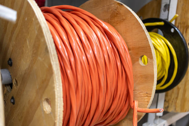 istock Large wooden spools - tightly wound orange and yellow cables - industrial setting - electrical wiring 1982629455