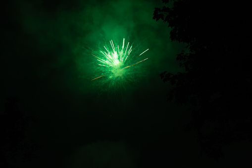 Burst of green fireworks at night - vibrant green streaks and sparks - smoke clouds - celebration, new years day, fourth of july, canada day. Taken in Toronto, Canada.