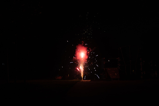Roman candle firework emits colorful explosion, sparks, light and smoke. Plenty of room for copy on both sides.