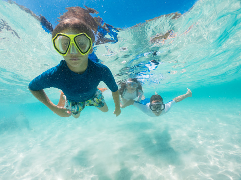 Teenagers having fun swimming and snorkel in a clear blue water