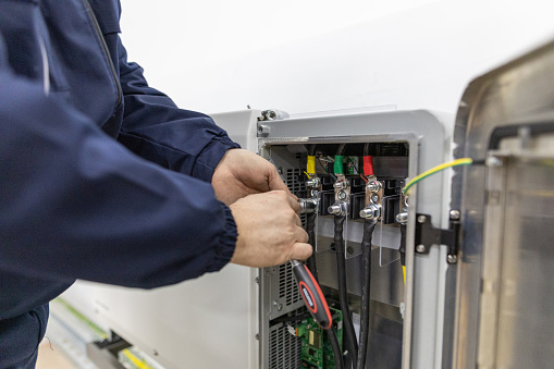 Mature male electricians working in an electrical system control cabinet