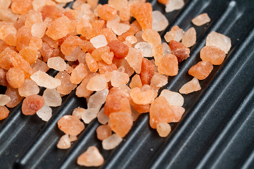 Pink Himalayan grains of salt, on black surface