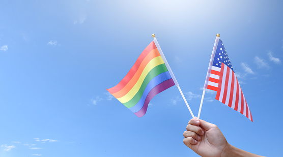 Rainbow flag and United States of America national flag holding in hand, soft and selective focus, concept for celebration of lgbtq+ in pride month around the world.
