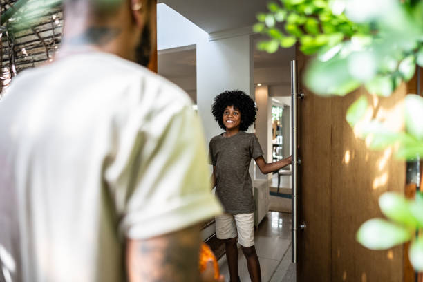 istock Boy opening front door and greeting brother 1982811378
