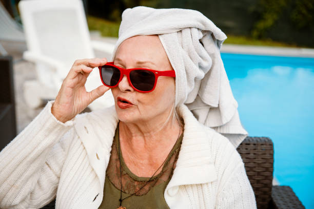 Portrait of Beautiful Senior Woman with red sunglasses and towel on head having a Spa day on Vacation