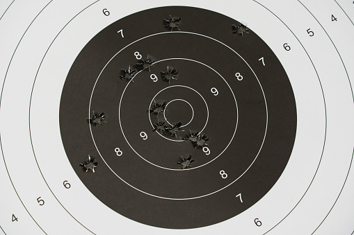 A paper target for shooting with holes from pistol bullets in the center, close-up photo. High quality photo
