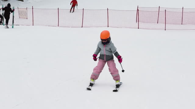 Adventurous Little Skier: 8-Year-Old Hits the Slopes in Pink Snowsuit and Orange Helmet, Little Girl Learn to Ski, Winter activity