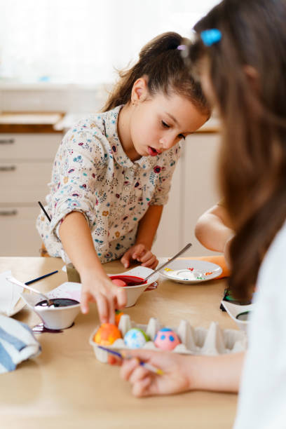 istock Two girls sitting at the table and dying eggs for the Easter holiday 1982953106