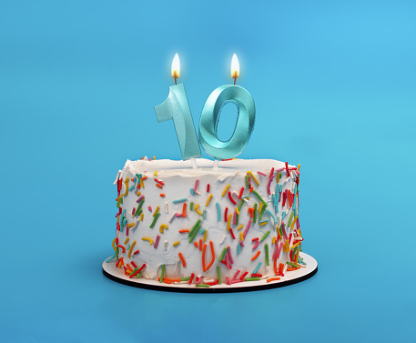 10 shaped candle light on happy birthday cake on blue