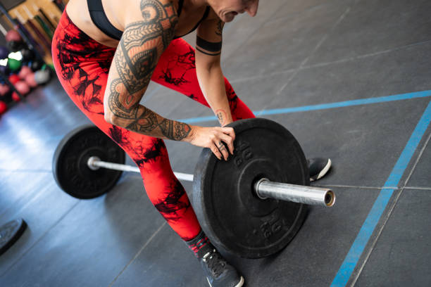 istock Woman adding weight to a bar for weightlifting 1983024970