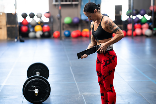 Strong woman preparing to weightlifting using safety belt in a cross training gym