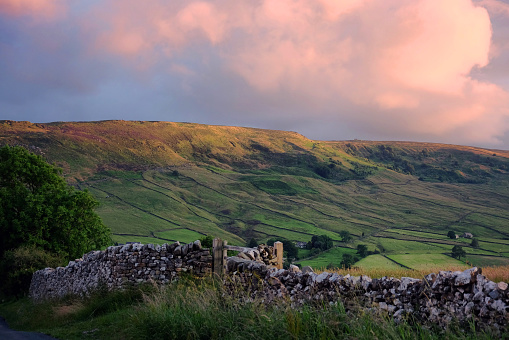 A drystone wall and view looking south over toward Burnsall and Thorpe Fell, during sunset, in the Yorkshire Dales, North Yorkshire.