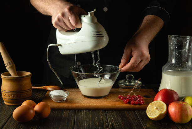 istock Chef prepares an egg omelette with milk using a hand-held electric mixer. Concept of preparing delicious breakfast in restaurant kitchen 1983118912