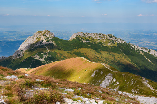 Polish Tatra Mountains, high mountain hiking trail leading to mountain peaks, mountain landscape with valleys and slopes, view on a sunny summer day.View of the Giewont mountain peak.