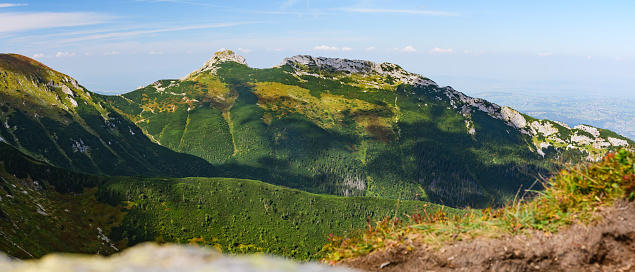 Polish Tatra Mountains, high mountain hiking trail leading to mountain peaks, mountain landscape with valleys and slopes, view on a sunny summer day.View of the Giewont mountain peak.