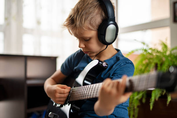 istock Cute little boy aged 7 is playing an electric guitar 1983153638
