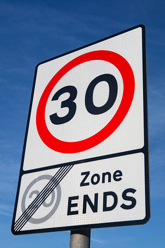 A UK 30-mile-an-hour sign indicating that the previous 20-mile-an-hour limit has ended.  In Eastbourne, UK.  In England, Scotland and Northern Ireland, all roads with lamp posts are restricted to 30mph unless drivers are otherwise directed.  Wales recently (and highly controversially) reduced the limit to 20mph.