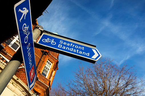 Direction signs, mainly for tourists, pointing to the sea front, the bandstand, and the railway station. The signs are in the centre of Eastbourne, East Sussex, UK.