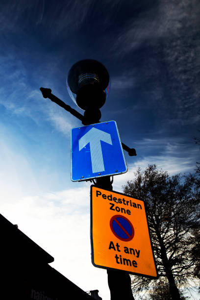 Pedestrian Zone The signs at the entrance to a pedestrian zone, indicating a one way street, and no waiting (which means you can drop off or pick up but you cant hang around, and you definitely cant park).  The shot is taken at dusk in Eastbourne, East Sussex, UK. The signs are fixed to a lamp post, which appears to be of a historic design (wiuth the bars on either side for the lamp lighters ladder) but is in fact a modern faux-historic post. song title stock pictures, royalty-free photos & images