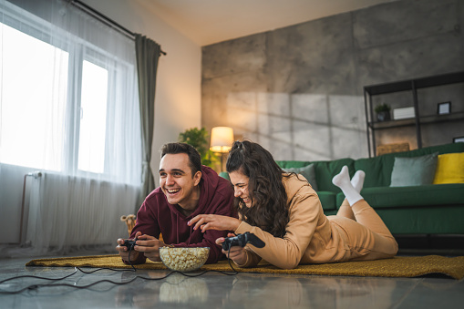 Adult couple man and woman caucasian husband and wife or boyfriend and girlfriend play console video games at home hold joystick controller have fun leisure joy and bonding concept