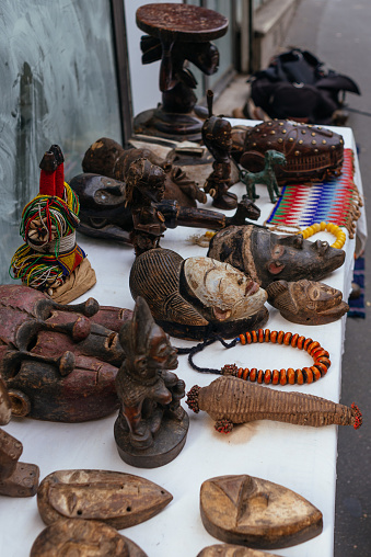 Close up view of African wooden masks, tribal figures and necklaces on sale at flea market in Paris, France