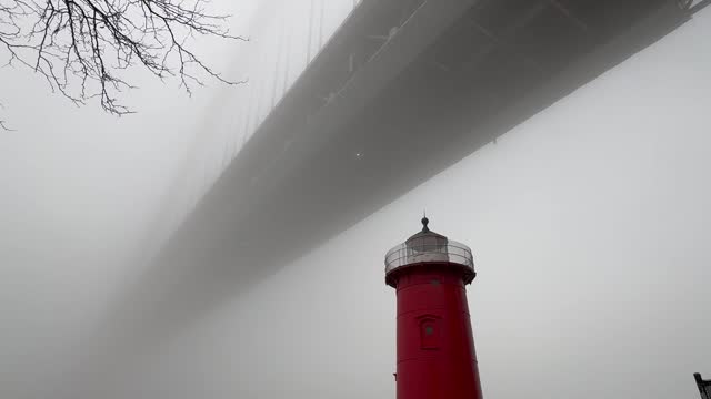 Little Red Lighthouse under the George Washington Bridge flashing a red light on a foggy winter day in New York City