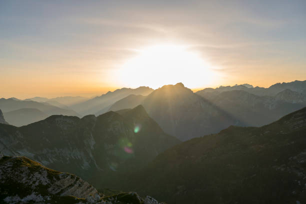 Portrait of smiling senior woman standing on mountain during sunrise.