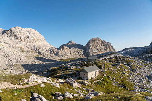 Mountain refuge Prehodavci in Triglav national park on sunny day, clear sky, mountain range in background.
