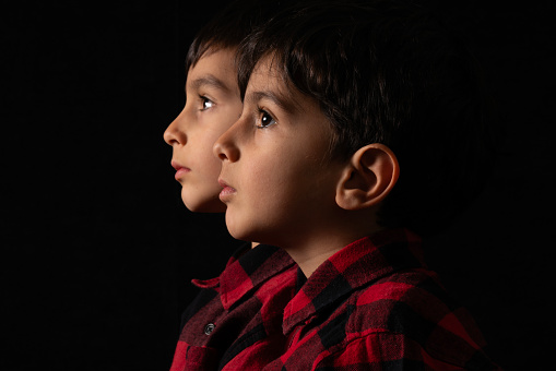 Side profile portrait photos of the brothers. little brothers wearing lumberjack shirts standing side by side. It was shot in a studio environment with a full frame camera.