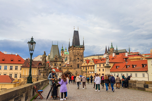 Prague, Czech Republic - March 24, 2023: Tourists walking on the famous Charles bridge in Prague, Czech Republic
