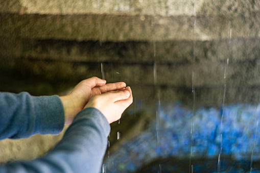 Kid hands under the water flow in fontain in Mziuro park, Tbilisi